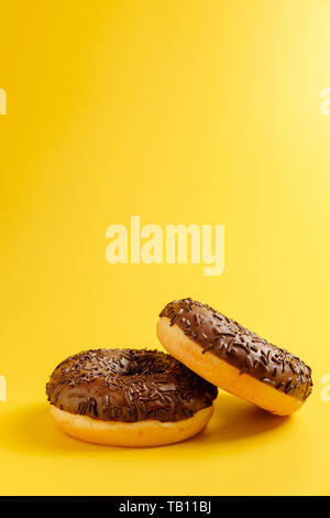 black donuts on yellow background top view Stock Photo