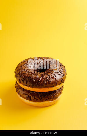 black donuts on yellow background top view Stock Photo