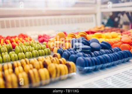 Assortment of colorful macaroons on cafe showcase. Variety of macaron flavours. Sweet almond cakes in store. French biscuits. Stock Photo