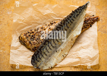 Two Scottish hot smoked mackerel fillets, S. scombrus, with cracked black pepper bought from a supermarket in the UK. Mackerel are a source of Ome Stock Photo