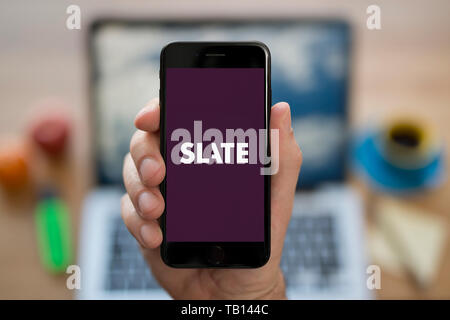 A man looks at his iPhone which displays the Slate Magazine logo (Editorial use only). Stock Photo