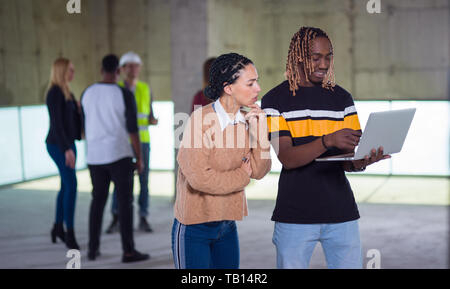 young multiethnic team of business people in group, architect and engineer on construction site checking documents and business workflow using laptop  Stock Photo