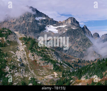 USA, Washington, North Cascades National Park, Black Peak rises above fog and fall-colored lower slopes, view west from Okanogan National Forest. Stock Photo