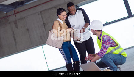 young multiethnic team of business people in group, architect and engineer on construction site checking documents and business workflow using laptop  Stock Photo