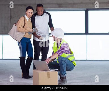 young multiethnic team of business people in group, architect and engineer on construction site checking documents and business workflow using laptop  Stock Photo