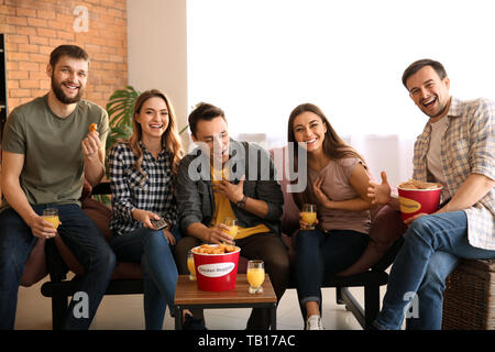 Group of friends eating nuggets while watching TV at home Stock Photo