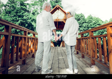 Happy couple holding hands and standing on the bridge. Stock Photo