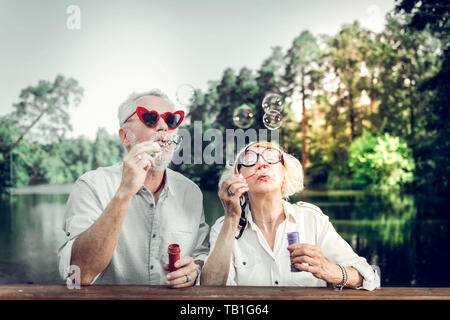 Close-up of husband and wife having fun while blowing bubbles Stock Photo