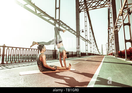 Yogi doing a handstand supported by her male partner Stock Photo