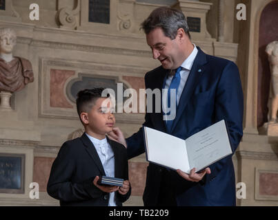 Munich, Germany. 29th May, 2019. Kenan Büyükhan from Nuremberg receives the Christophorus Medal from Markus Söder (CSU), Prime Minister of Bavaria. Kenan is the youngest recipient of the medal. He got his sister out of a car after the rear tire caught fire. Credit: Peter Kneffel/dpa/Alamy Live News Stock Photo
