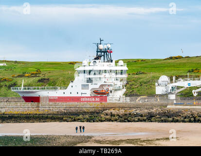 Aberdeen, Scotland, United Kingdom, 29th May 2019.  A Ostensjo Rederi Norwegian research/survey vessel, Edda Sun, leaves the harbour and sets sail for the North Sea as people enjoy an evening walk on the beach near Footdee and the old fisherman cottages Stock Photo