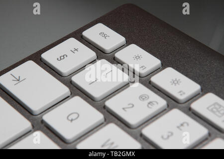 Apple iMac keyboard on an office desk focusing on the escape key. Stock Photo
