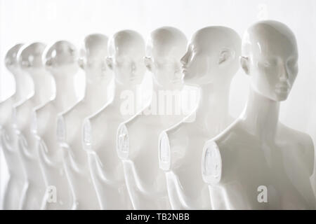 Bright Photo of Plastic Woman Mannequins Standing in The Line, With One Looking to Another Direction then the Others on white Background Stock Photo