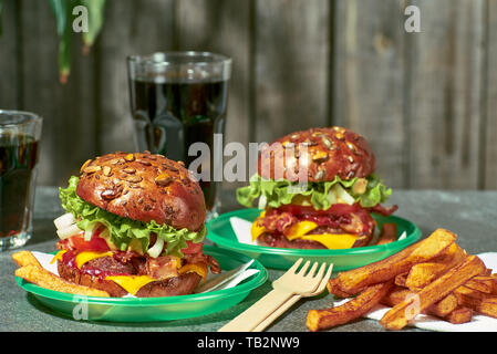 Two hamburgers with fries and drink on stone table Stock Photo