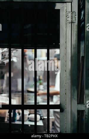 Chef working in the kitchen behind the fenced door Stock Photo