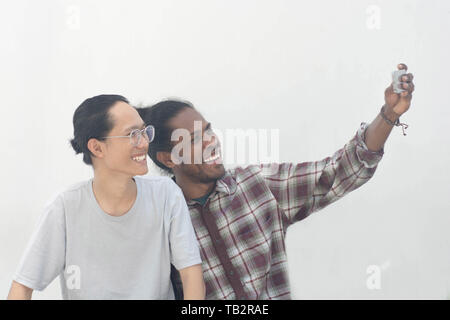 two friend with different ethnic taking selfie together and smiling, asian and black man selfie together Stock Photo