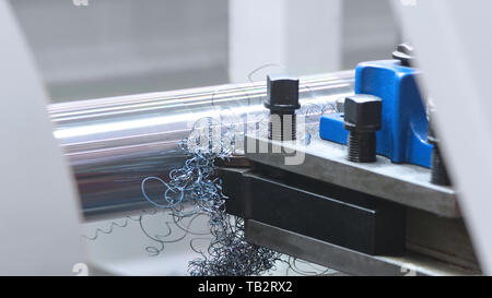 metalworking  industry: cutting steel metal shaft processing on lathe machine in workshop. Selective focus on tool Stock Photo