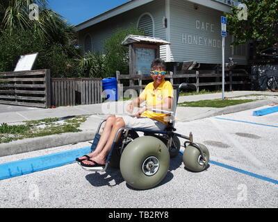 Disabled woman in beach wheelchair at Honeymoon Island State Park in Dunedin, Florida, USA, May 10, 2019, © Katharine Andriotis Stock Photo