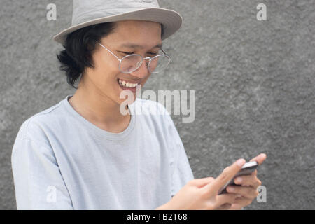 attractive young asian man with hat and glasses using smarphone Stock Photo