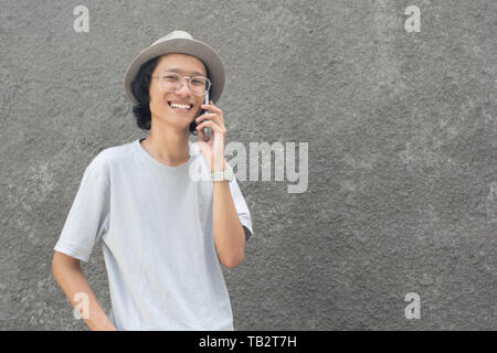 attractive young asian man with hat and glasses using smarphone Stock Photo