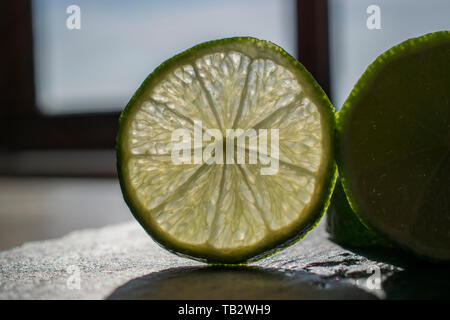 Slice of lime on a chopping board at the window Stock Photo