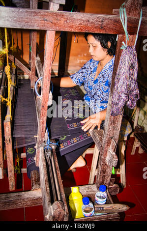 BALI, INDONESIA - FEBRUARY Circa, 2019. Unidentified mature indonesian woman making a traditional hand made carpet in factory. Each carpet can take mo Stock Photo