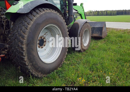 Tractor with front end loader on grass. Low angle side view with copy space. Stock Photo