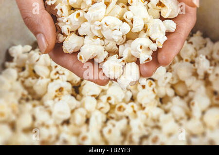 High angle view of hands contain popcorn from a bowl. Stock Photo