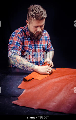 Leather master performs leather working for a new product . Stock Photo