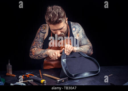 Professional Leather Worker producing leather goods at the desk. Stock Photo