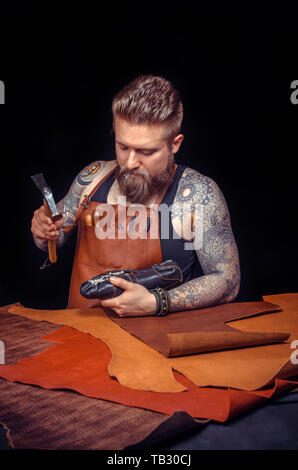 Currier of leather cutting out leather goods at the place of work Stock Photo