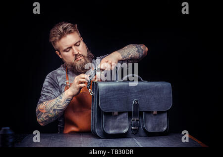 Leather Worker works with leatherwork at his workshop Stock Photo