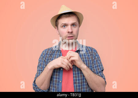 Shy young handsome man in summer hat is unsure Stock Photo