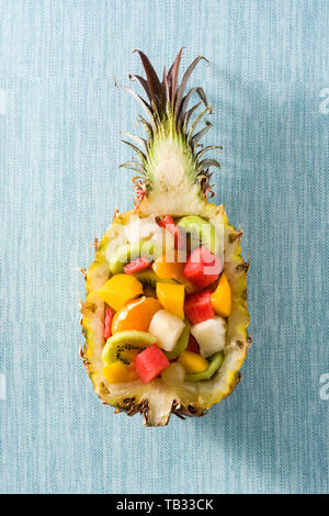 Mix fruit served inside pineapple on blue background Stock Photo