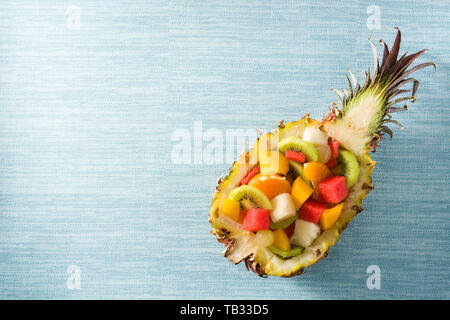 Mix fruit served inside pineapple on blue background Stock Photo