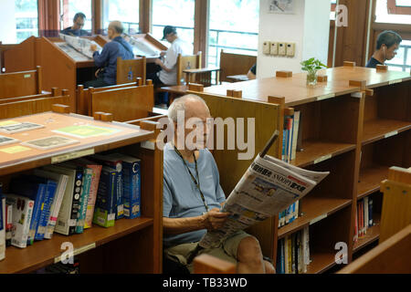 Elderly man reading a newspaper in Taipei Public Library Beitou Branch located in Beitou District, Taipei, Taiwan Stock Photo