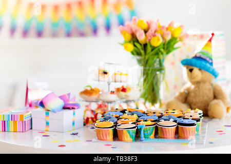 Cupcakes for kids birthday celebration. Jungle animals theme children party. Decorated room for boy or girl kid birthday. Table setting with presents, Stock Photo