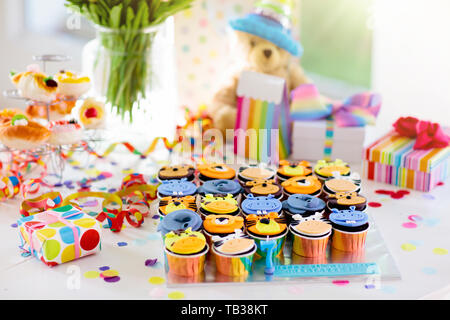 Cupcakes for kids birthday celebration. Jungle animals theme children party. Decorated room for boy or girl kid birthday. Table setting with presents, Stock Photo