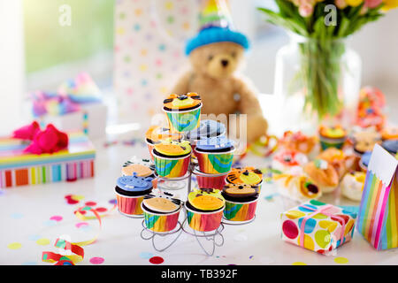 Cupcakes for kids birthday celebration. Jungle animals theme children party. Decorated room for boy or girl kid birthday. Table setting with presents, Stock Photo