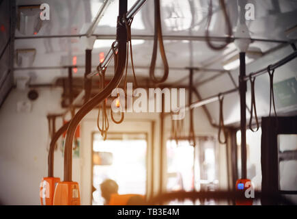 Travel around the city inside a public bus with black curved handrails illuminated by sunlight. Stock Photo