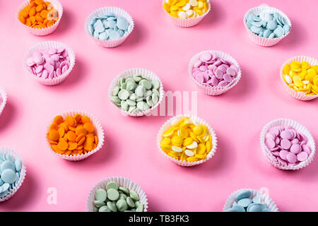 Multicolored chocolate frosting for making desserts in cupcake shapes on a pink background. Professional pastry chef concept Stock Photo