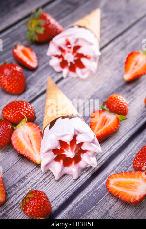 Ice cream cones with strawberries on a vintage wooden table summer. Focus on ice cream. Stock Photo