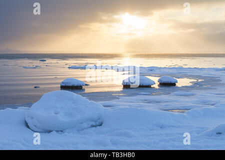 Sunset with snowy boulders and beach landscape. Baltic sea, winter time. Stock Photo