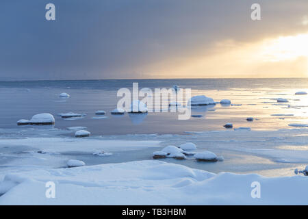 Sunset with snowy boulders and beach landscape. Baltic sea, winter time. Stock Photo