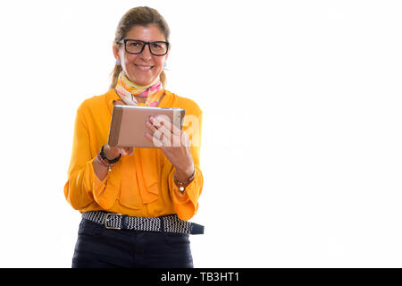 Studio shot of mature happy businesswoman smiling and using digi Stock Photo