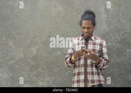 young bearded black man in casual dress using smartphone Stock Photo