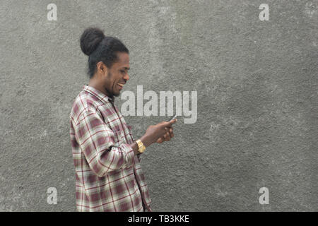 young bearded black man in casual dress using smartphone Stock Photo