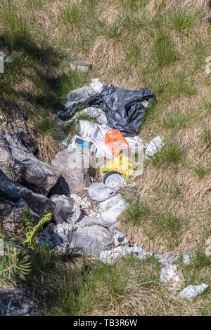 Pile of garbage on green grass in the nature in spring, showing a global problem for the environment Stock Photo