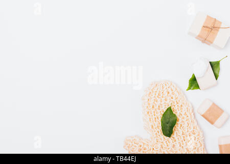 Bath soaps of different types and massage mitten on white background with copy space, flat lay composition. Stock Photo