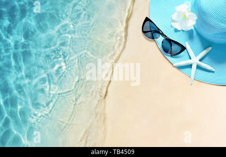 Hat and sunglasses on the sandy beach. Summer background. Stock Photo